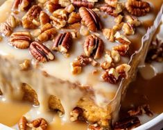 a piece of cake with pecans and icing on top in a white bowl