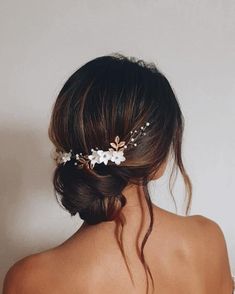 the back of a woman's head wearing a bridal hair comb with flowers on it