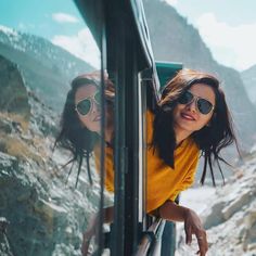 two women in sunglasses are looking out the window of a bus on a mountain road