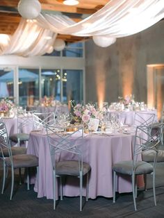 the tables are set with white linens and silver chairs