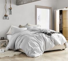 a bed with white sheets and pillows in a room