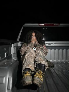 a woman sitting in the back of a pick up truck with her hands covering her face