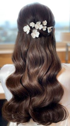 the back of a woman's head with long brown hair and flowers in her hair