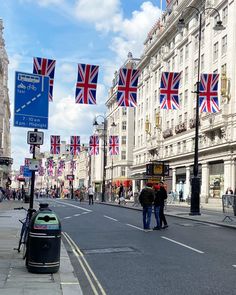 two men are standing on the street with british flags flying in the air above them