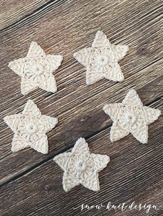 four crocheted stars sitting on top of a wooden table