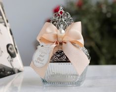 a small glass bottle with a bow on the top is sitting next to a greeting card