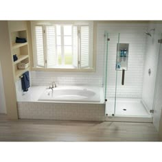 a bath tub sitting under a window next to a sink and shower stall in a bathroom