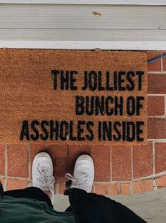 someone standing in front of a door mat that says the jolliest bunch of ankles inside