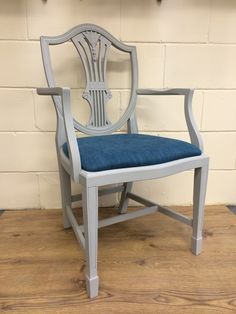 a chair with a blue cushion sitting on top of a hard wood floor next to a white brick wall