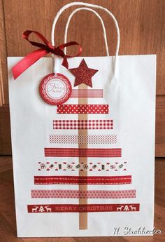 a paper bag with a christmas tree on it and a red ribbon around the top