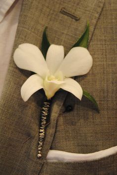 a white flower is placed on the lapel of a man's suit jacket