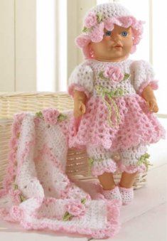 a crocheted doll is sitting next to a basket with a blanket on it