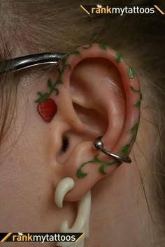 a child with fake ear piercings on their ears and behind the ear is a strawberry