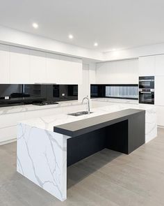 a large kitchen with marble counter tops and white cabinets, along with an island in the middle