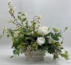 a vase filled with white flowers and greenery