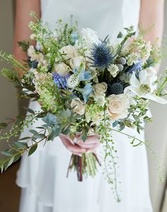 a bride holding a bouquet of flowers and greenery