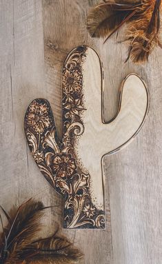 a wooden letter shaped like a cactus with feathers on the floor next to it,