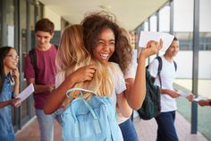 a group of young people walking down a hallway with one woman carrying a backpack and smiling at the camera