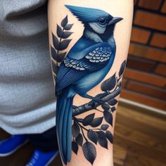 a blue bird sitting on top of a branch with leaves around it's legs