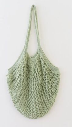 a green crochet bag hanging on the wall with no handles or hooks to hold it