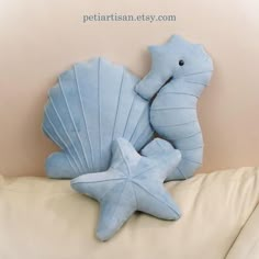 two stuffed sea animals sitting on top of a white couch next to a starfish