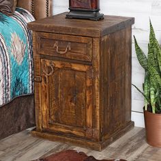 an old wooden cabinet next to a bed with a potted plant on top of it