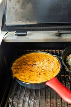 two pans filled with food cooking on an outdoor grill