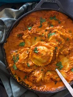 an iron skillet filled with food on top of a blue cloth and silver spoon