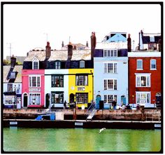 several colorful houses line the water in front of some buildings with windows and balconies