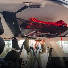 a man is holding up his luggage in the back of a car with its door open