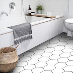 a white bathroom with black and white tile flooring in the bathtub, toilet and sink