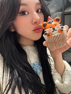 a woman holding up a cupcake with frosting on it