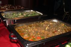 three trays filled with food sitting on top of a red tablecloth covered table