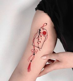 a woman's arm with a tattoo on it that has a tag and tassel