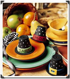 a table topped with plates covered in black and orange hats