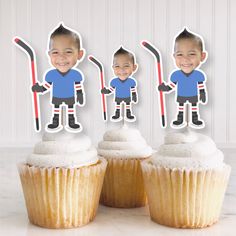 three cupcakes with stickers on top of them in front of a wall