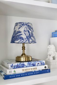 a blue and white lamp sitting on top of a bookshelf next to a book