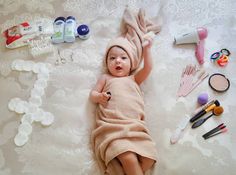 a baby wrapped in a towel is laying on the bed with other items around it