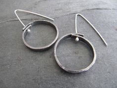 "Here are some simple affordable silver earrings that are easy to wear every day. These earrings are textured on the surface, formed into a circle, pierced, oxidized, buffed, and suspended from handmade polished sterling silver ear wires. The circle is about 1\" in diameter (25mm)" Handmade Round Silver-plated Wire Earrings, Minimalist Round Sterling Silver Earrings, Handmade Silver Circular Earrings, Minimalist Sterling Silver Open Circle Earrings, Artisan Silver Nickel-free Hoop Earrings, The Circle, A Circle, Ear Wires, Silver Earrings