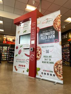 a pizza vending machine in a store next to a sign that says automated pizza oven is here