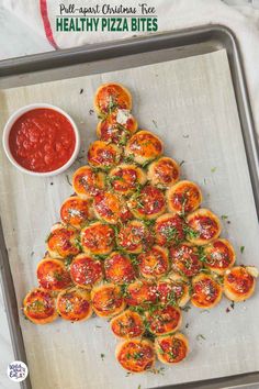 a christmas tree made out of mini pizzas on a baking sheet with ketchup