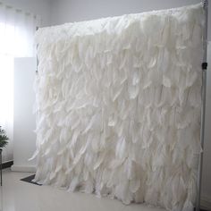 a room with a large white wall covered in feathers