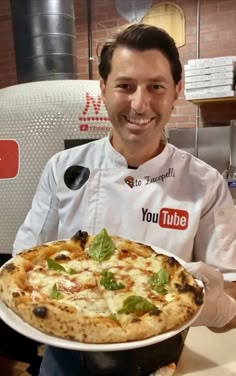 a man holding a pizza in front of him