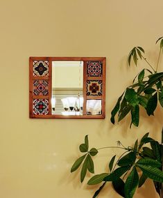 a mirror hanging on the wall next to a potted plant