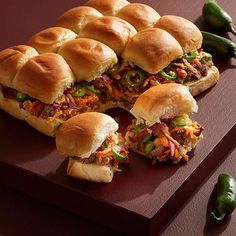 several sandwiches cut in half on a cutting board with green peppers around the edges and sides