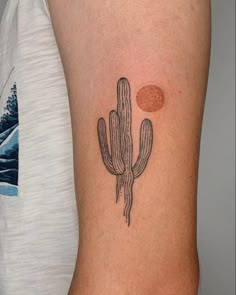 a small cactus tattoo on the right side of the left arm, with an orange dot above it