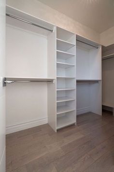 an empty closet with white shelves and wooden floors