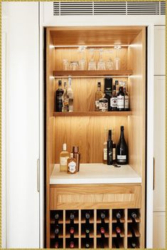 a wine rack with bottles and glasses on it next to a cabinet full of liquor