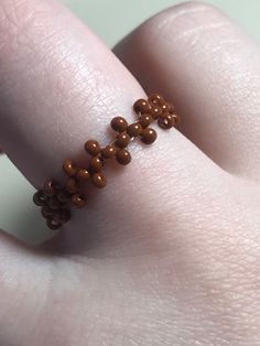 a close up of a person's hand wearing a ring with beads on it