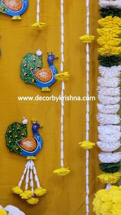 decorative wall hangings with peacocks and flowers on yellow fabric, decorated with white string